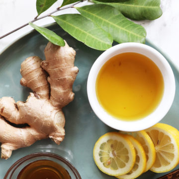 Lemon Ginger Tea on top of a teal plate with ginger, lemons, and turmeric.